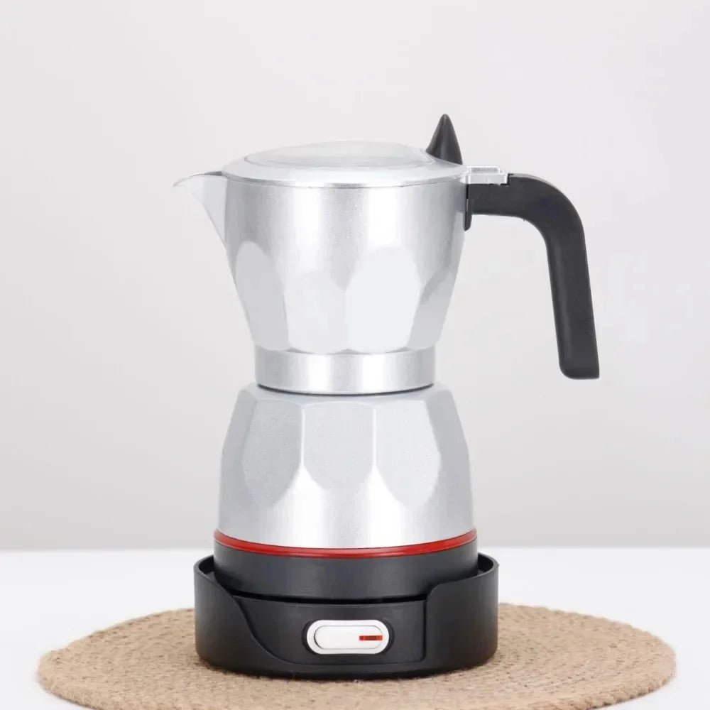 Silver aluminum electric moka pot coffee maker with black handle and base on a round woven mat.