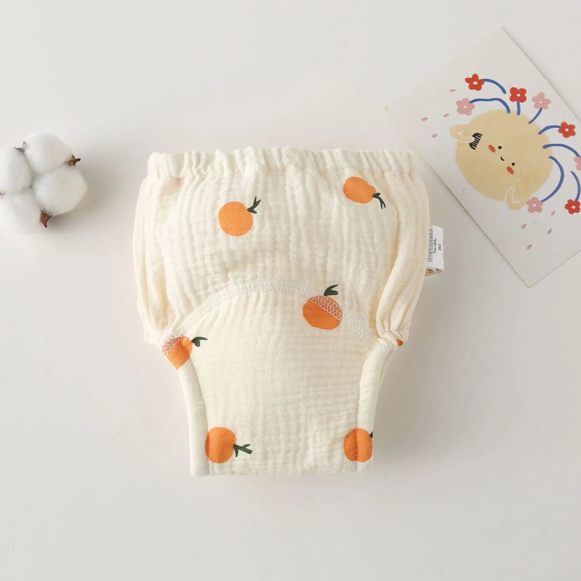 Cloth baby diaper, size 80, featuring a cute orange fruit print on soft cream fabric. Baby care essentials.