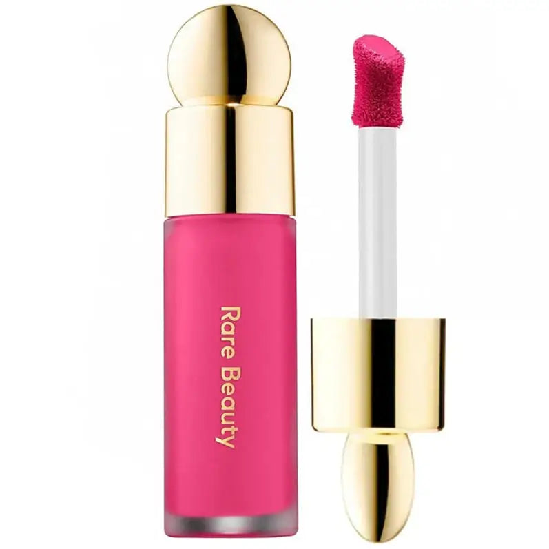 Rare Beauty rose liquid blush and lip tint in vibrant pink with gold cap and applicator wand on white background.