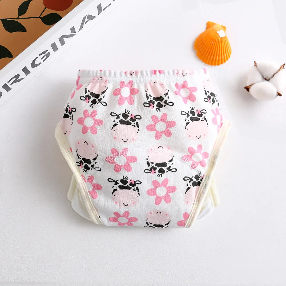 Reusable cotton baby training diaper with cute cow and pink flower print on white background.