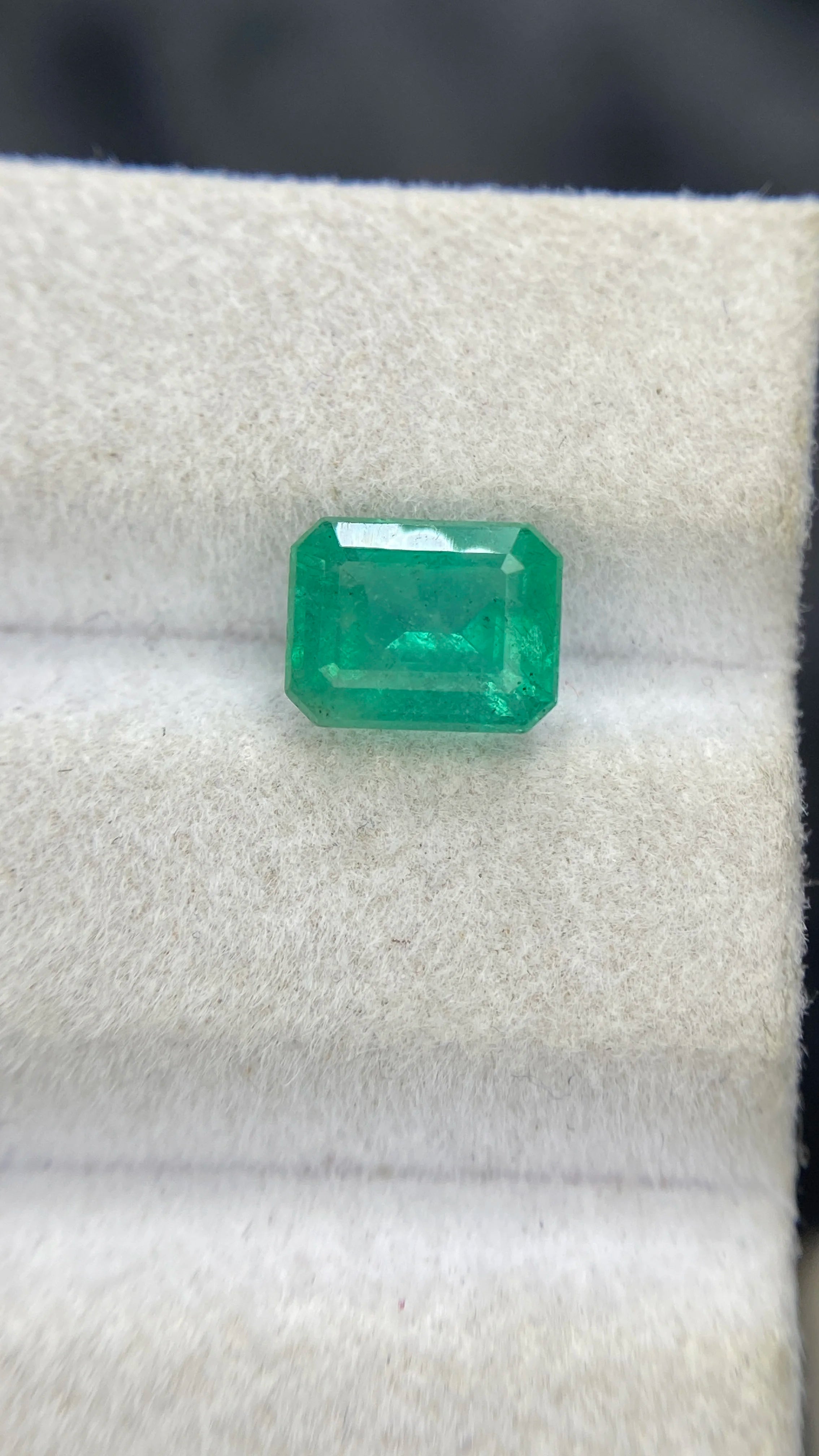 Faceted emerald-cut green gemstone, centered on display