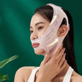 A person wears a light pink, V-line facial slimming bandage with patterned detailing over their chin and jaw.