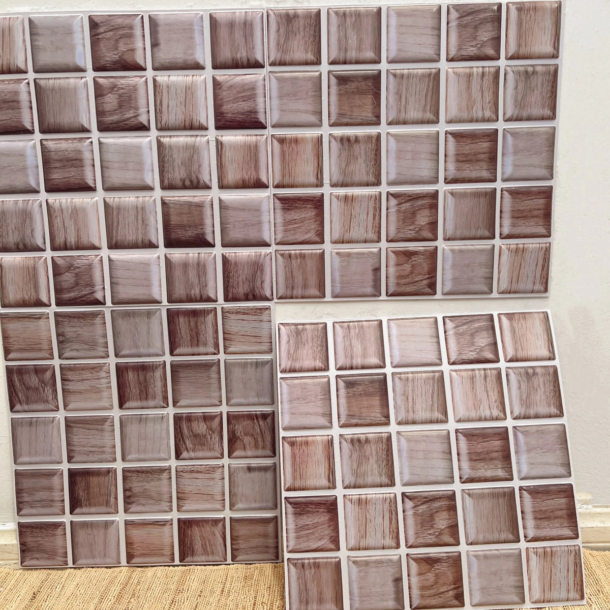 Peel-and-stick marble tile backsplash sheet with square tiles in taupe, cream, and dark brown
