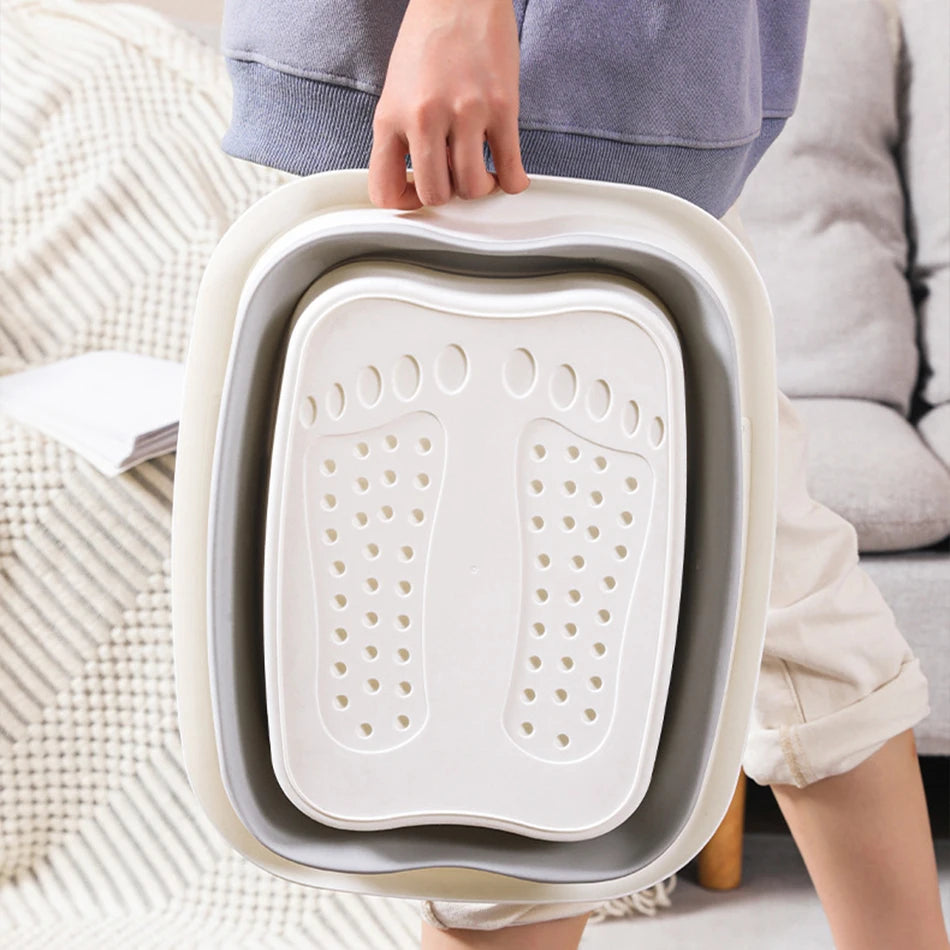Portable white and grey foldable foot bath tub with textured massage base, held for easy storage and travel.