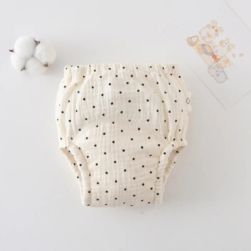 Cream baby cloth training diaper with black polka dot print, made of soft absorbent cotton fabric.