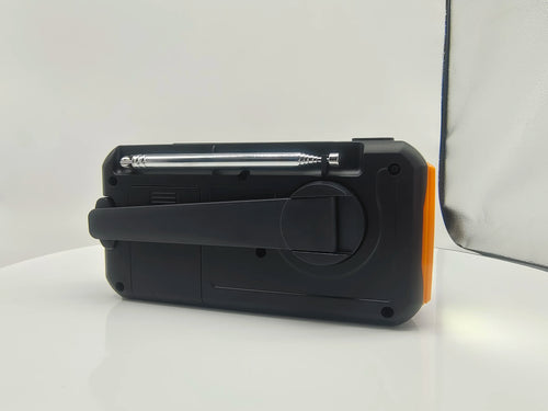 Black emergency hand crank radio with a telescopic metal antenna and charging handle against a white background.