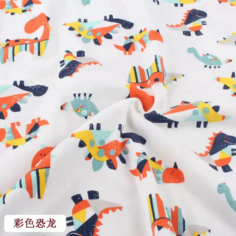 Tidesmit white knit jersey fabric featuring a colorful, abstract dinosaur print for children's clothing.