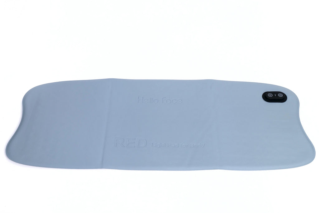 Large, flat, light-blue rectangular red light therapy mat with embossed branding and a black control button.