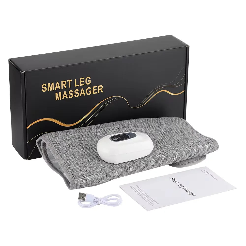 Grey fabric smart leg massager with white handheld controller, USB charging cable, and manual in a black gift box.