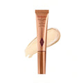 Charlotte Tilbury Hollywood Beauty Light Wand in rose gold tube with shimmering champagne liquid highlighter swatch.