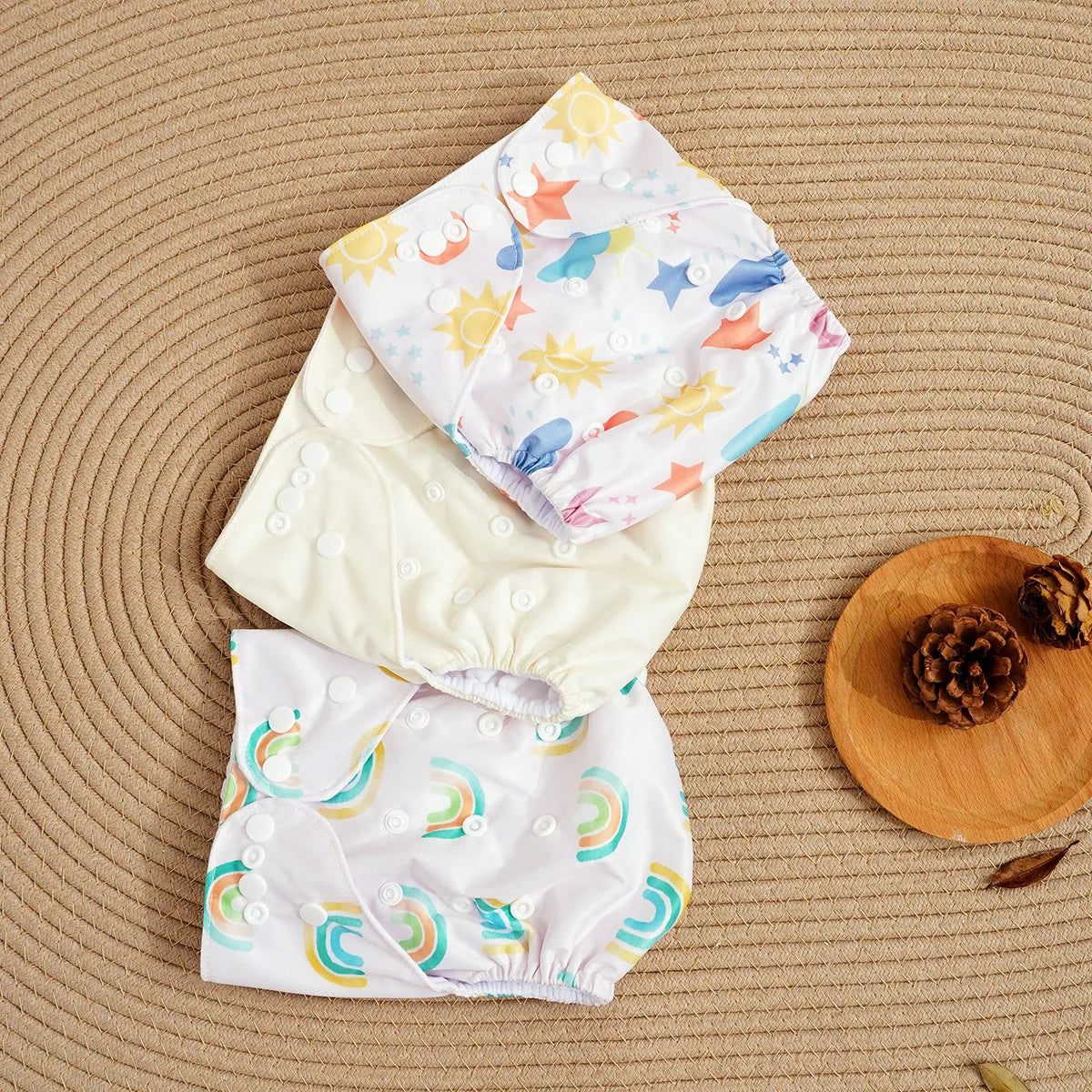 Three adjustable cloth diapers featuring sun, rainbow, and cream patterns for eco-friendly baby care.