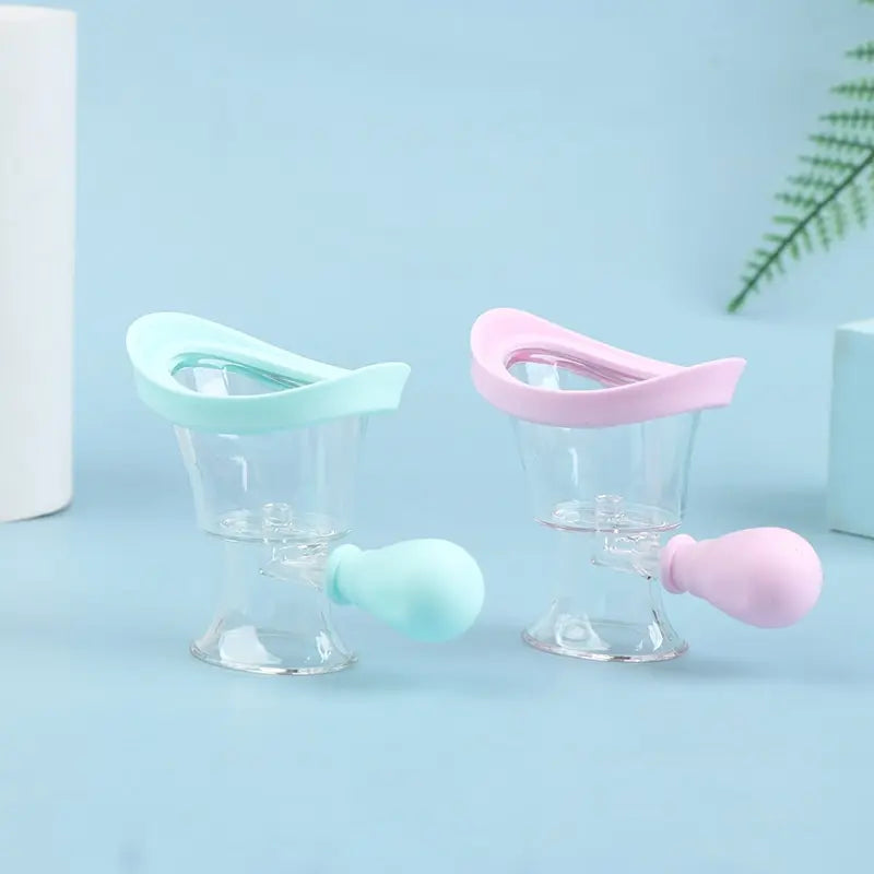 Two reusable soft silicone eye wash cups with clear basins and blue and pink squeeze bulbs for eye flushing.