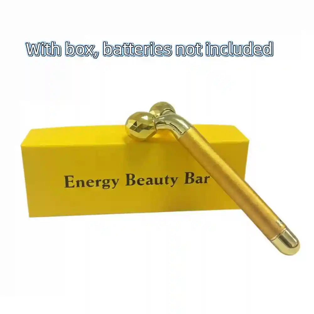 Gold-colored facial roller massager with faceted dual spheres, resting on a yellow box labeled "Energy Beauty Bar."