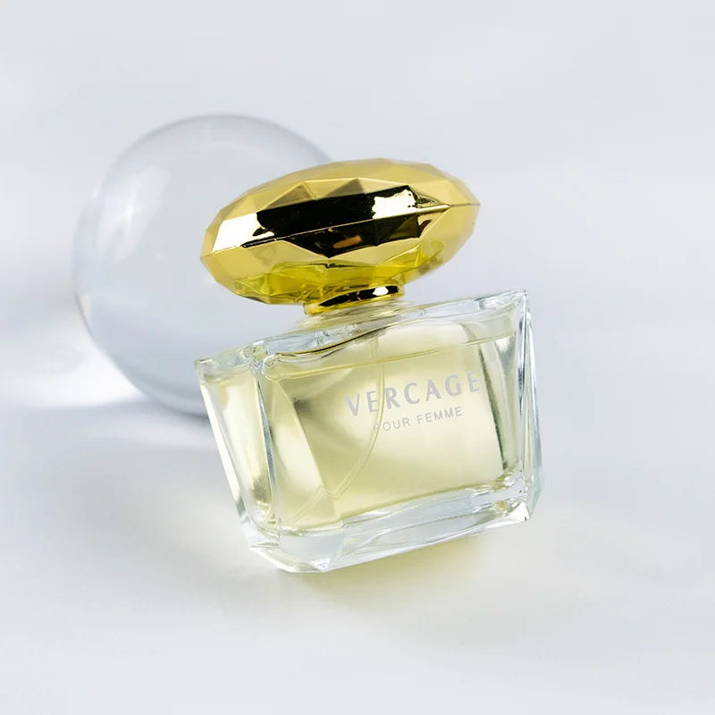 Luxury 50ml perfume bottle with clear glass, floral scent, and faceted gold cap against a white background.