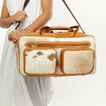 Western-style genuine leather and cowhide duffel bag with front pockets and shoulder strap for travel.