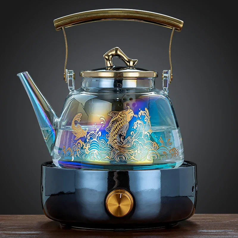 Iridescent glass tea kettle with gold koi fish pattern, metal handle, and electric base heater for home tea brewing.