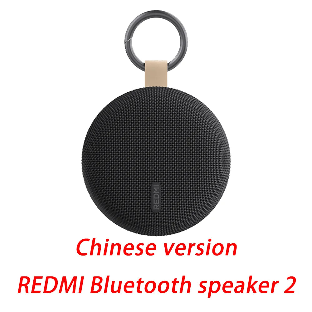 Round Bluetooth speaker with keyring and beige strap, black mesh body
