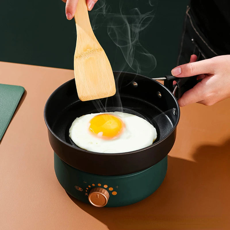 Black nonstick fry pan attachment with egg, on teal electric cooker base
