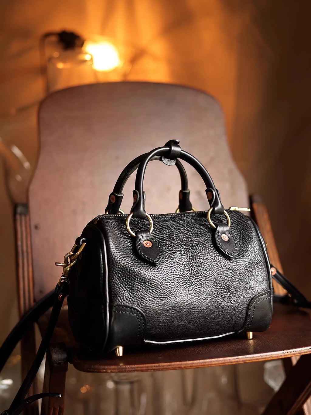 Black genuine cowhide leather small handbag with top handles, gold hardware, and vintage designer style.