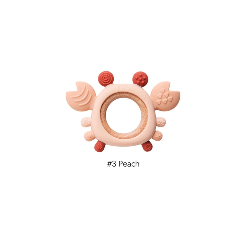 Peach silicone and wood crab baby teething ring for soothing sore gums.