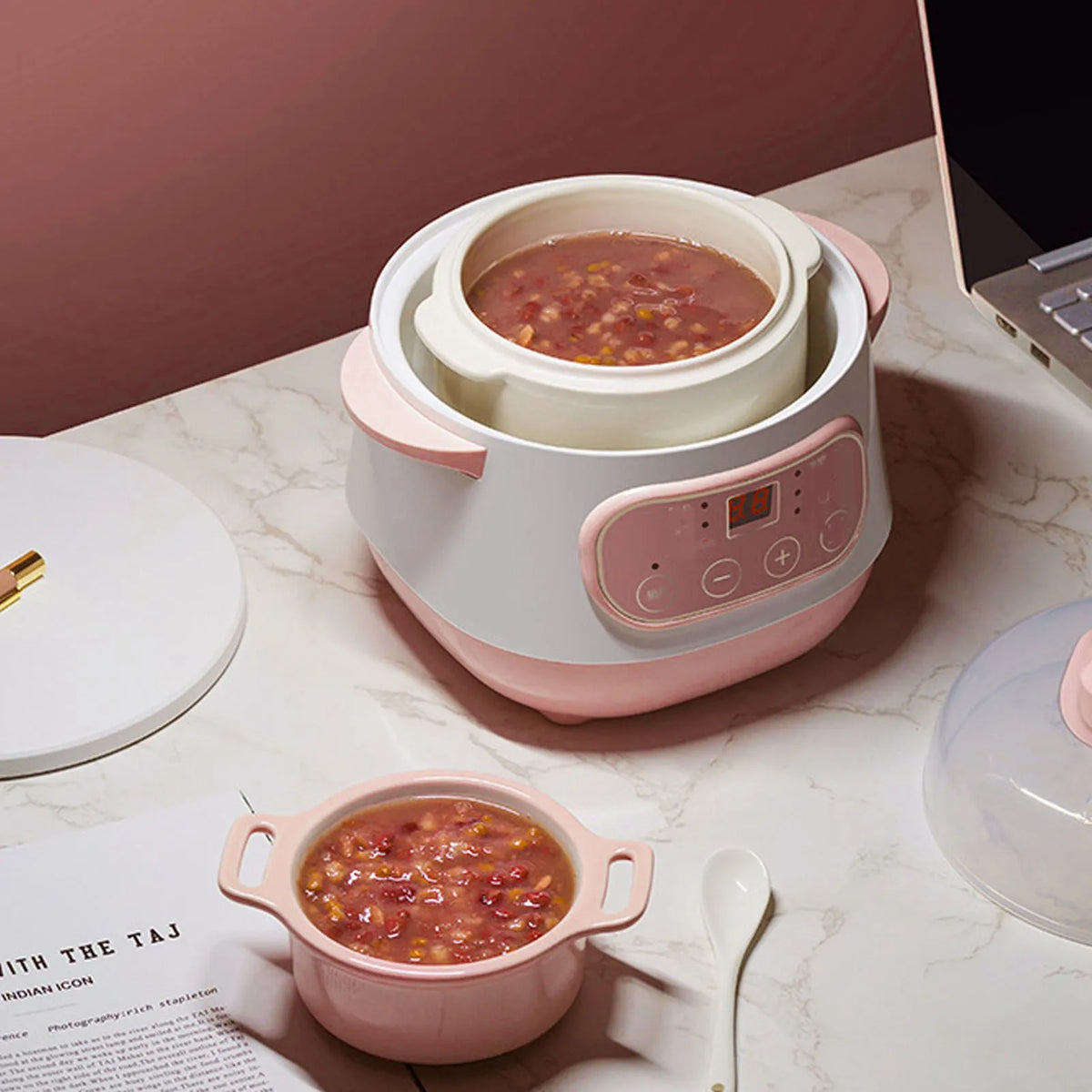 Pink mini electric rice cooker with lid open, showing stew inside and front control panel