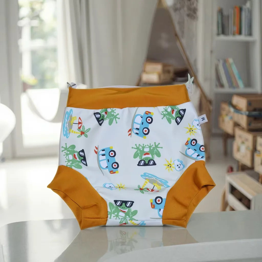 Size M baby swim diaper with cute frog and car summer print, featuring yellow elastic trim. Premium baby care product.