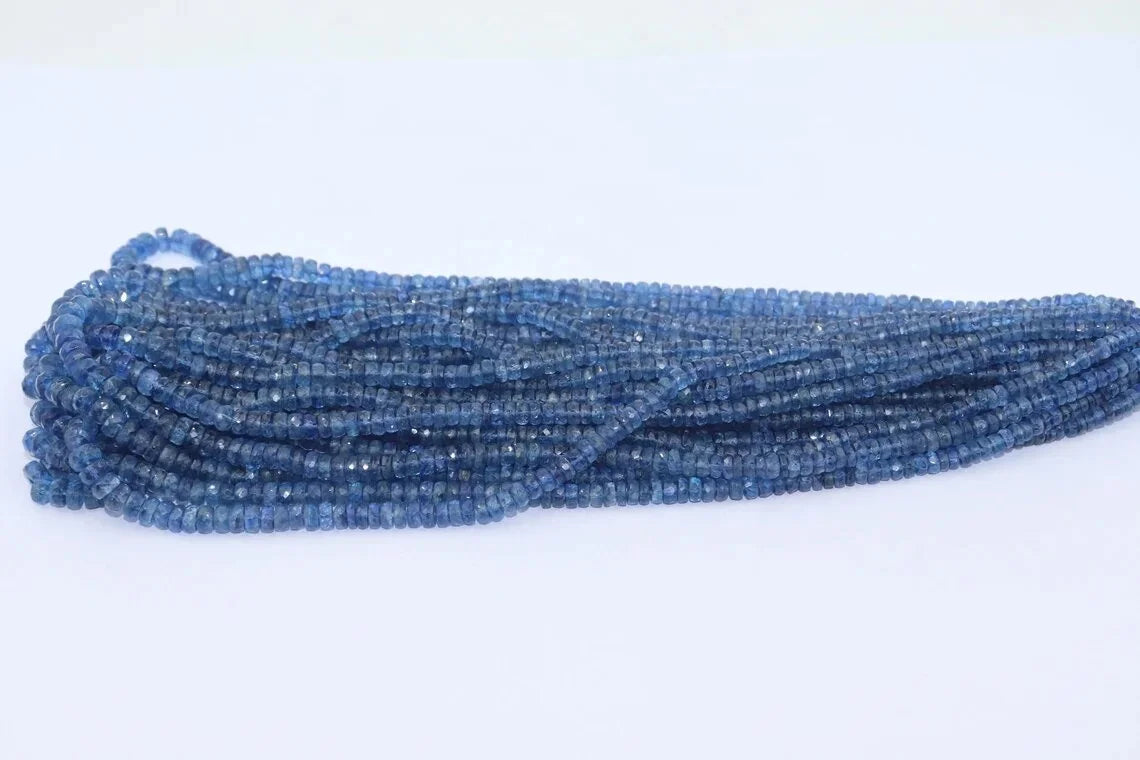 Kyanite rondelle bead strand, faceted blue beads laid out, drilled holes throughout