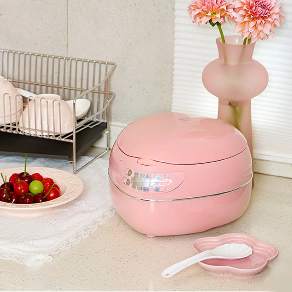 Pink mini heart rice cooker on countertop near dish rack and fruit plate