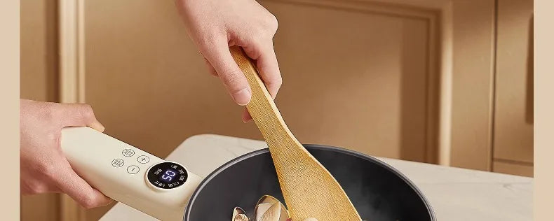 White electric cooking pot with wooden spatula stirring food in the pan
