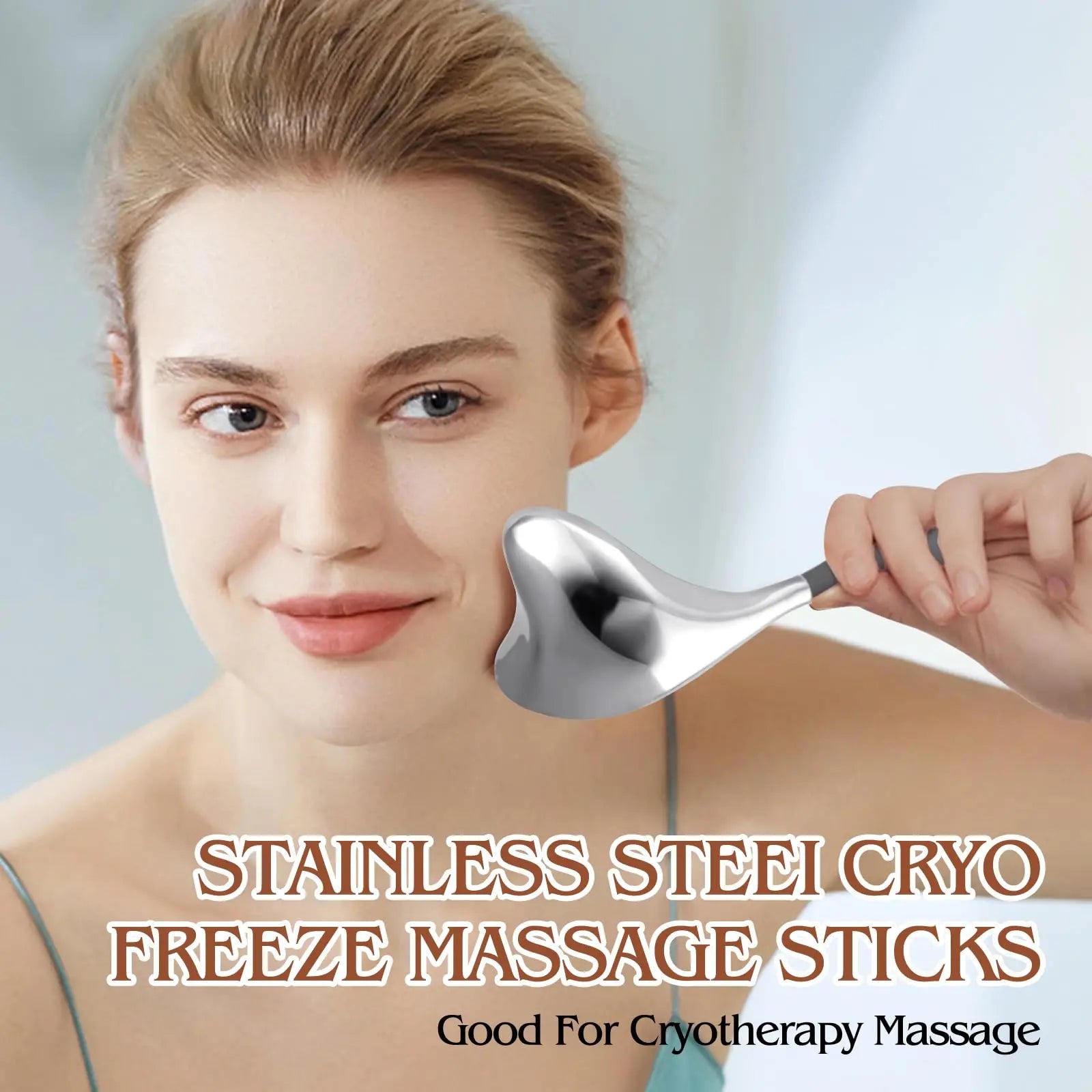 Woman using a heart-shaped, silver stainless steel cryo massage stick on her cheek for facial skin care.