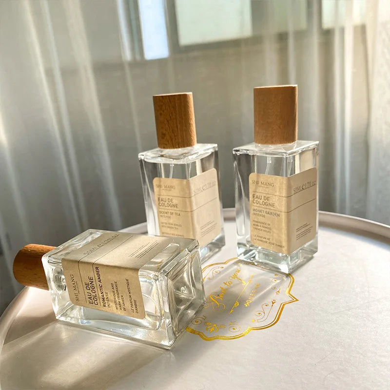 Shi Mang Eau de Cologne 50ml: Woody, tea & floral scents in luxury rectangular glass bottles with minimalist wood caps.