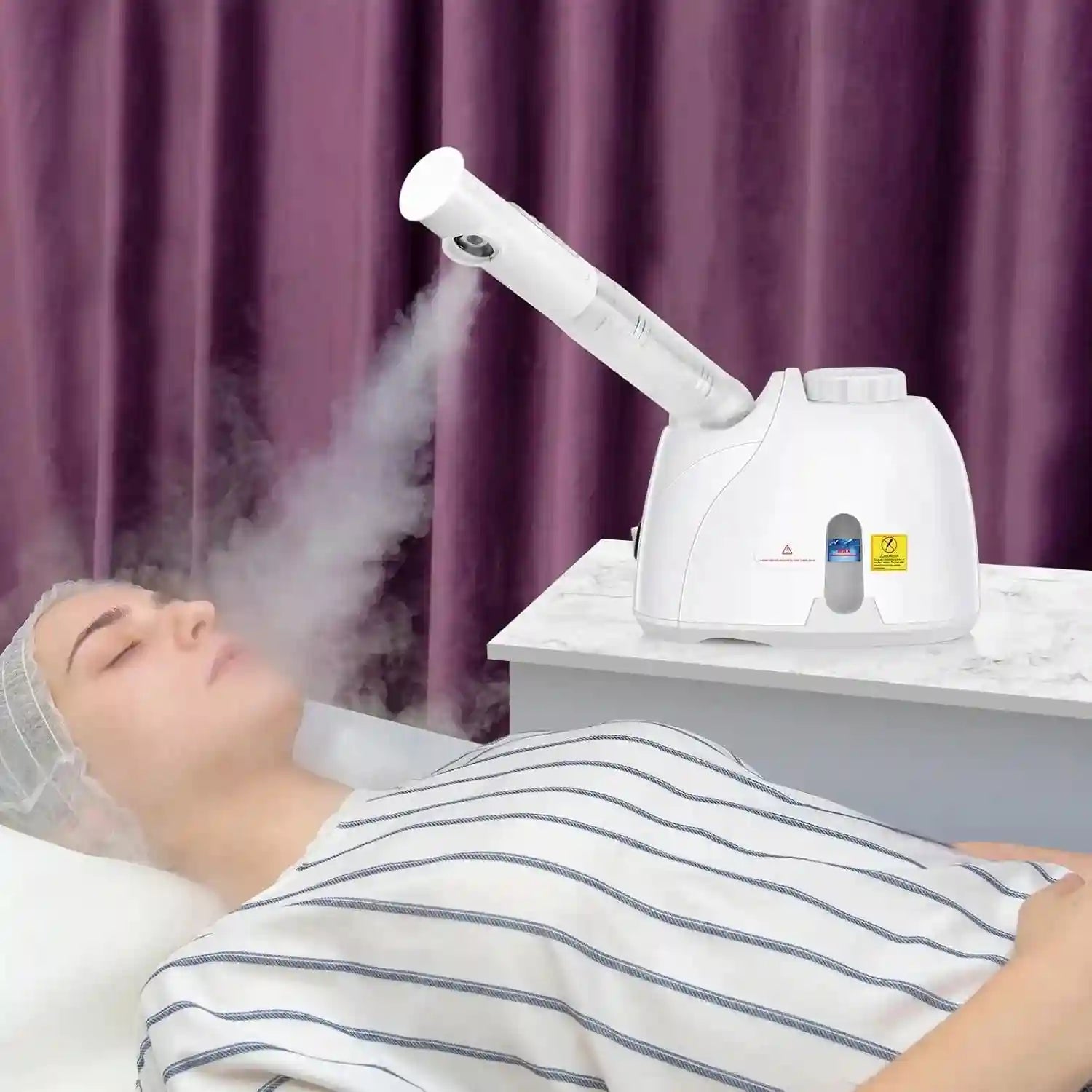 White facial steamer with adjustable nozzle providing deep hydrating steam to a woman’s face for at-home skin cleansing.