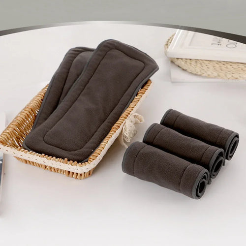 Set of 5 charcoal grey reusable bamboo baby diaper inserts for cloth diapering in a decorative basket.
