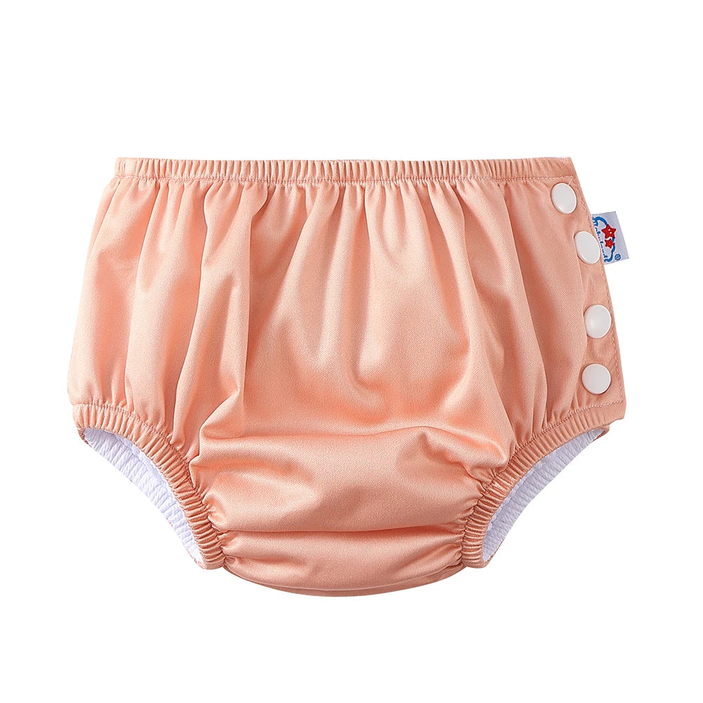 Solid peach reusable baby swim diaper with white snap buttons for adjustable sizing.
