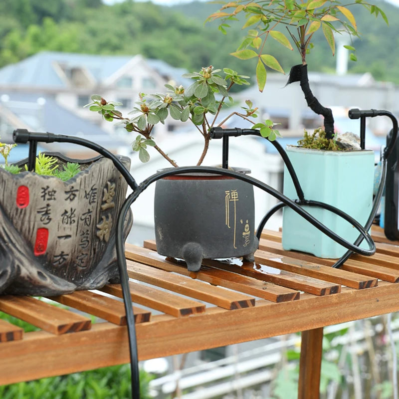 Drip irrigation kit with black tubing and stake emitters on a greenhouse potting bench
