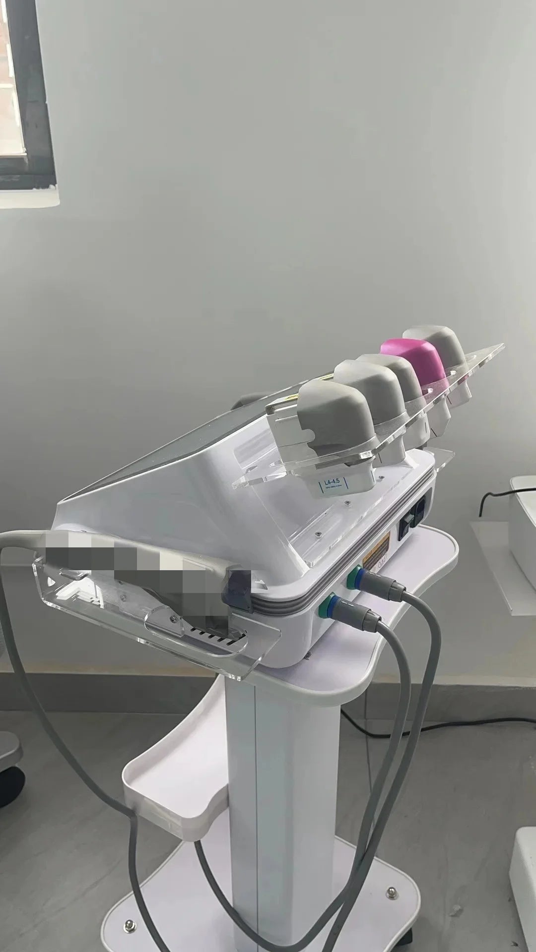 White 7D beauty SPA machine on a mobile stand with a row of different colored applicator heads in a clear holder.