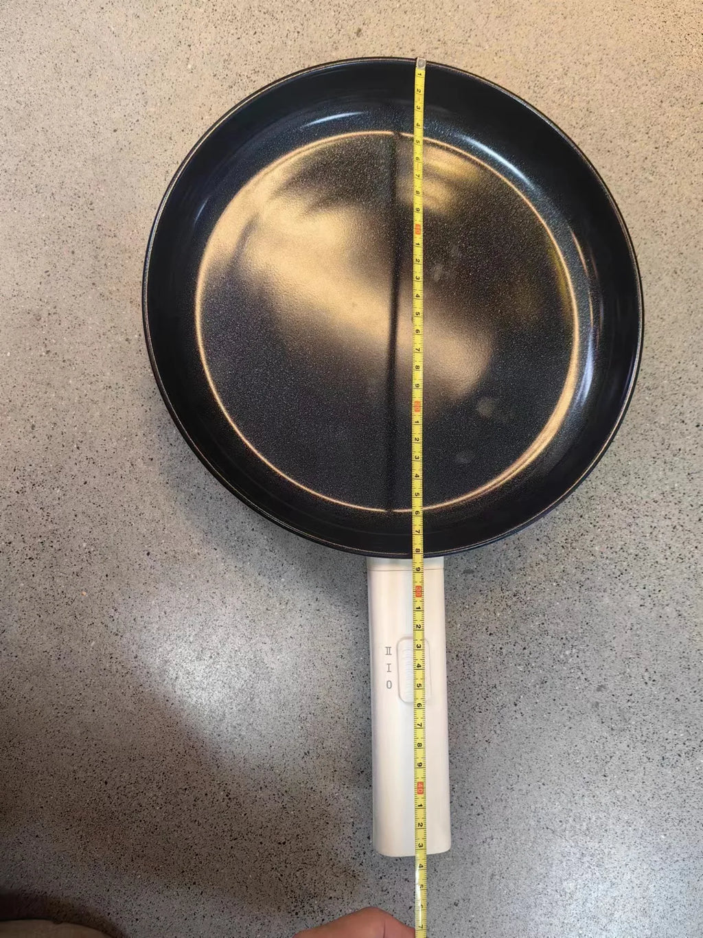 Electric frying pan with black nonstick interior and white handle, length checked with ruler
