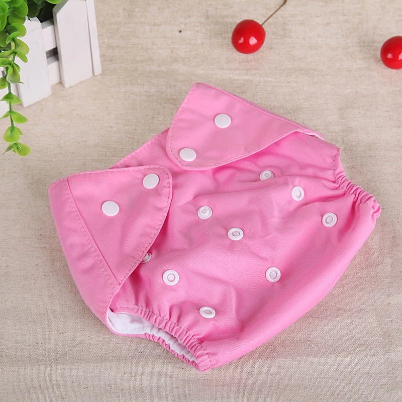 Adjustable pink cloth diaper for babies with white snap buttons, reusable infant baby care gear.