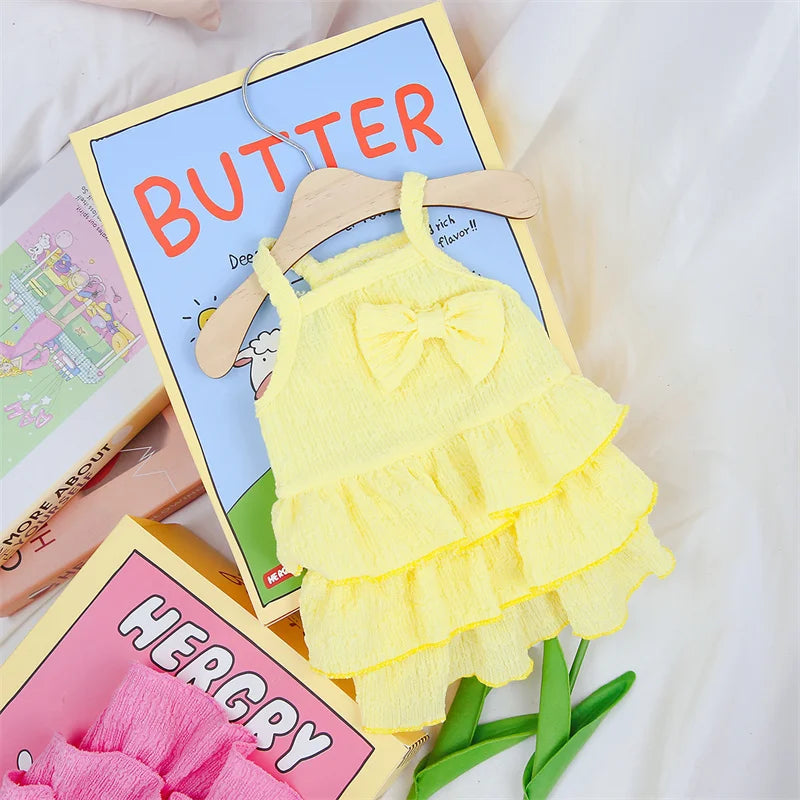 Tidesmit yellow textured dog dress with a bow detail and tiered ruffled skirt, displayed on a hanger.