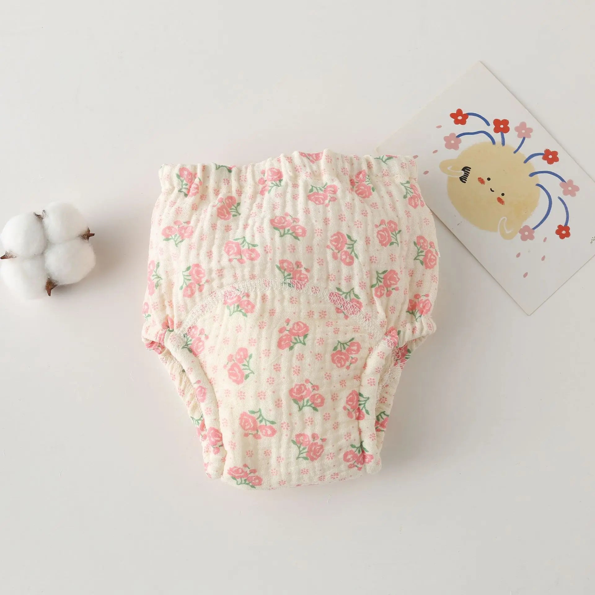 Soft cotton baby care training diaper with pink floral rose pattern on cream background.