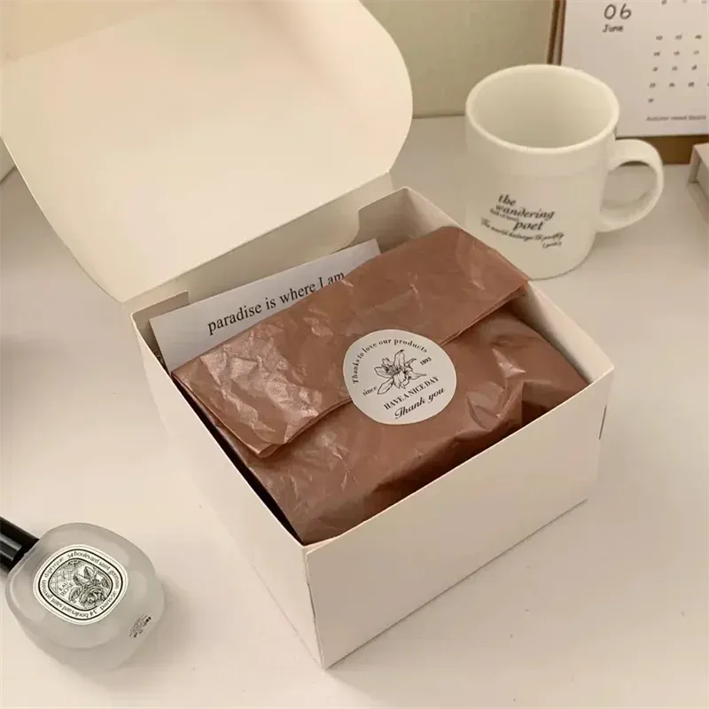 Round custom logo sticker on brown paper inside a white gift box.