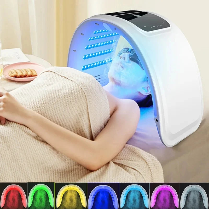 White arched LED facial therapy device emitting blue light over a person lying down, with seven color options shown.