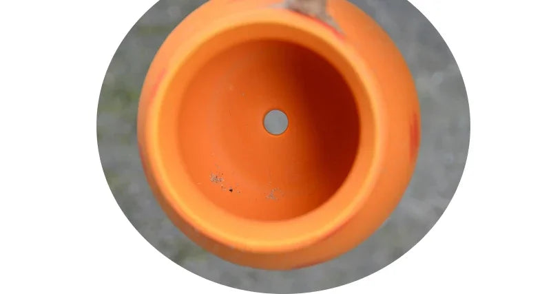 Orange hanging ceramic flowerpot with round drain hole, top view