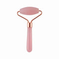 Pink resin jade roller for facial massage, anti-wrinkle skin care, and face lifting with rose gold metal frame.