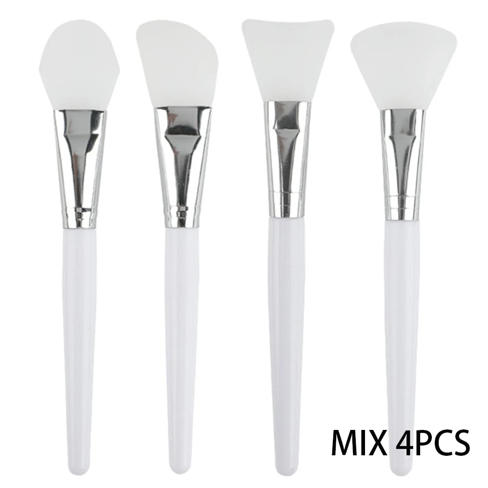 Four white silicone face mask brushes with different head shapes, silver ferrules, and white plastic handles.