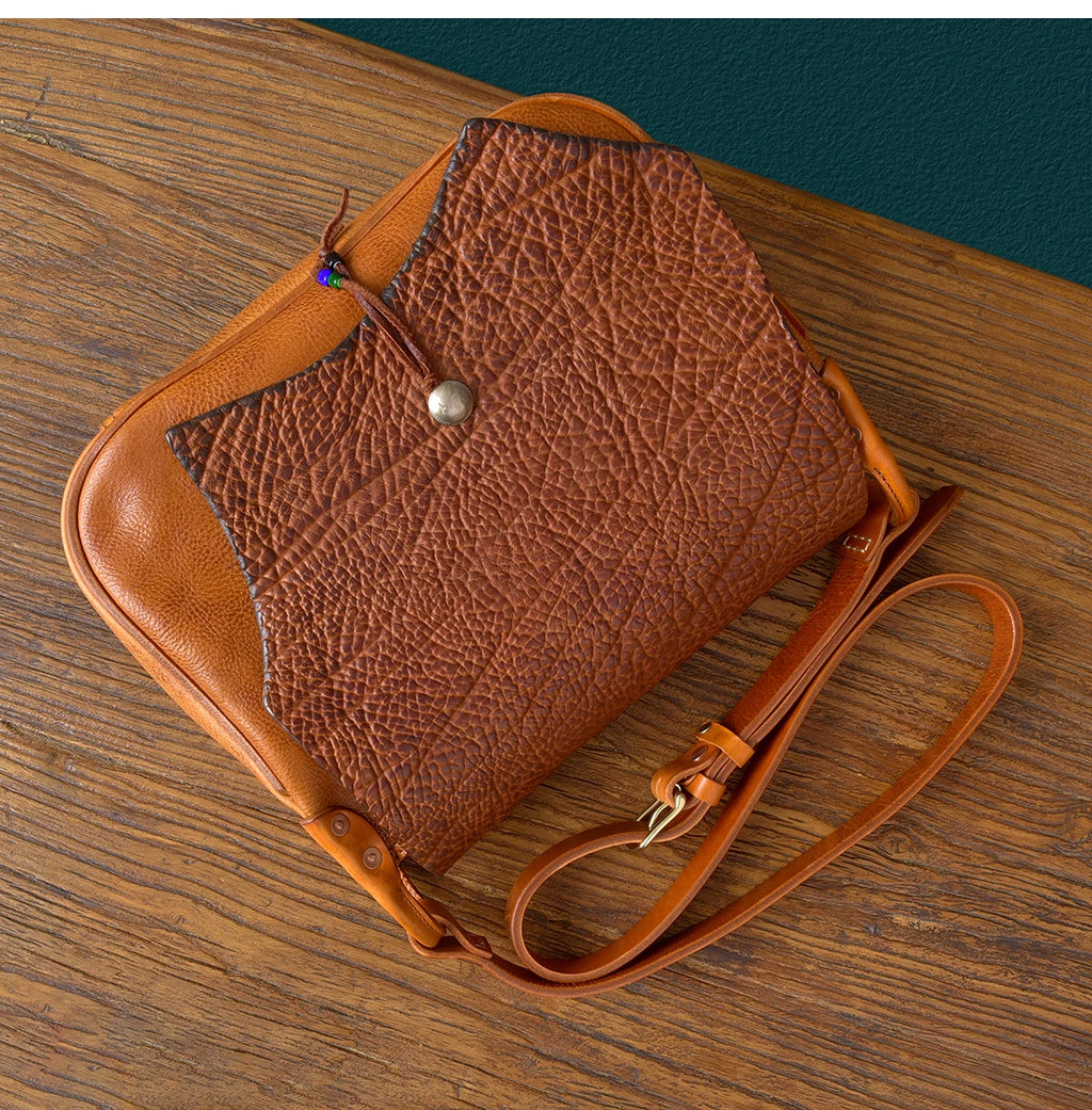 Vintage handmade messenger bag in tan cowhide leather with a textured, rugged fold-over flap and adjustable strap.