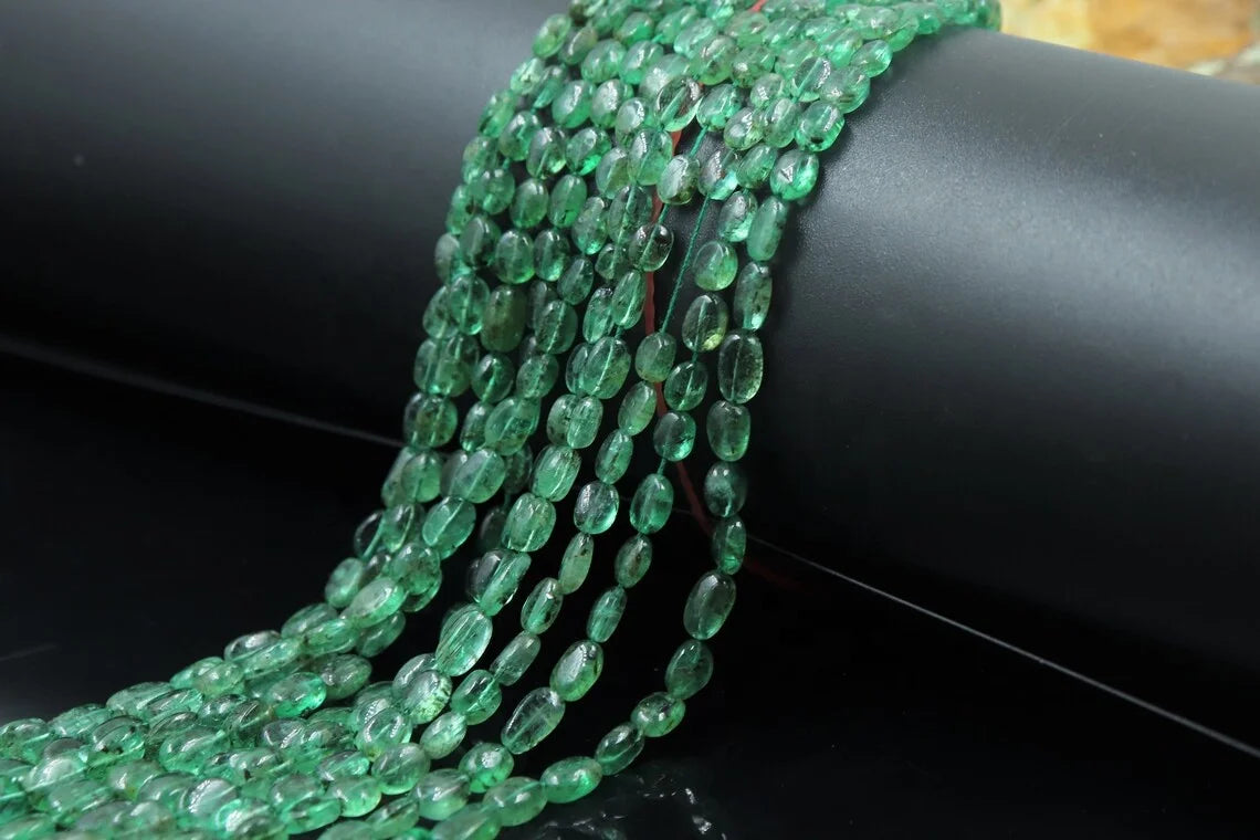 Close view of green oval bead strands, drilled holes and glossy finish