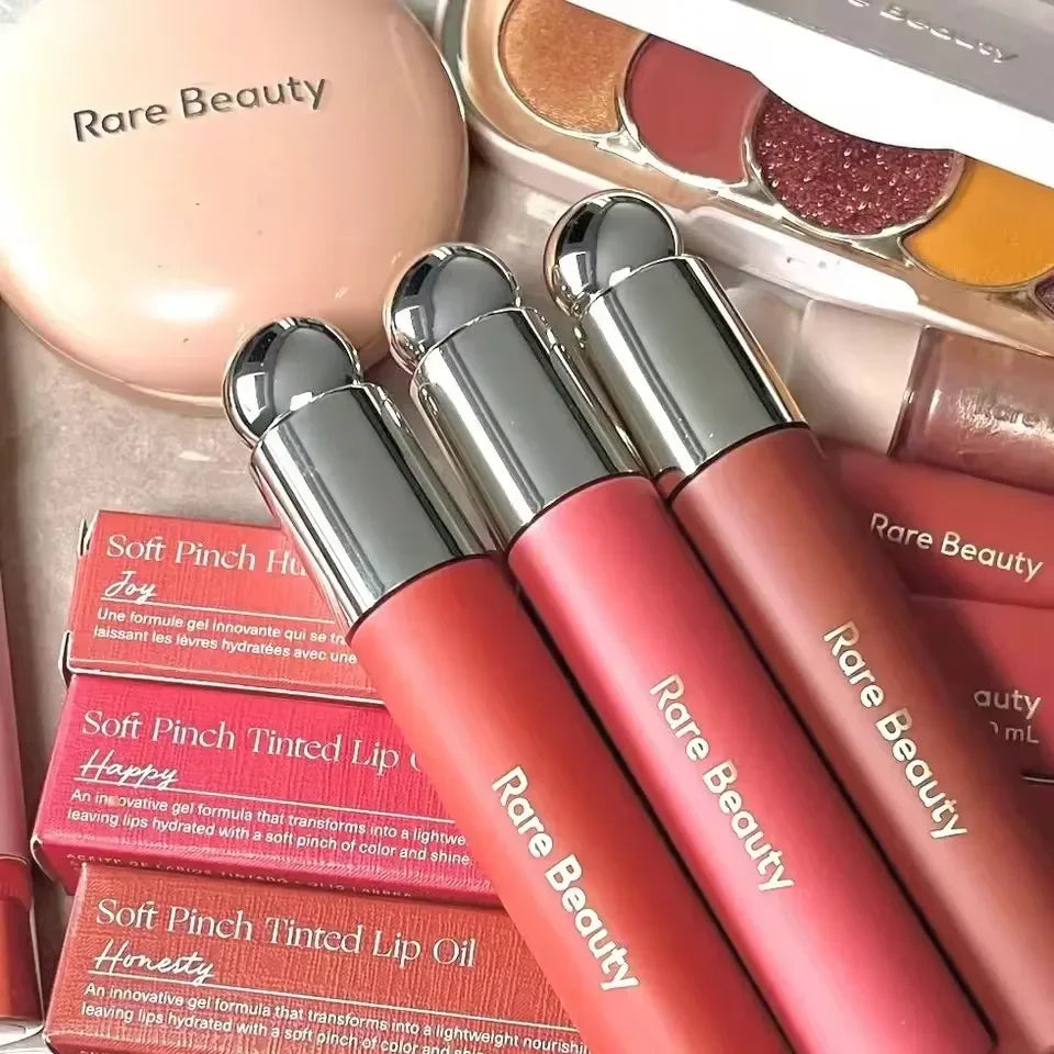Rare Beauty lip oils in rich, matte-finish colors with a smooth, moisturizing texture and elegant silver packaging.