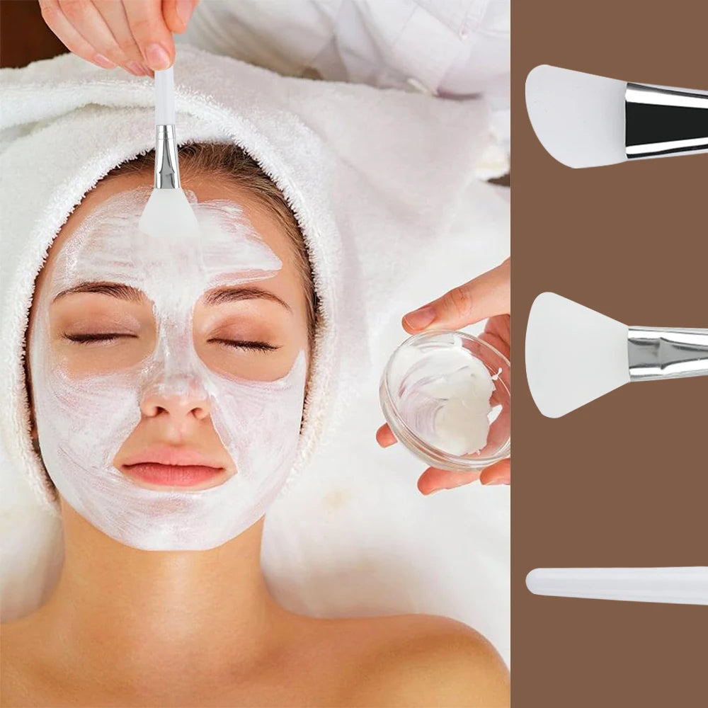 White silicone face mask brushes with metallic silver ferrules and white handles, shown applying a cream facial mask.