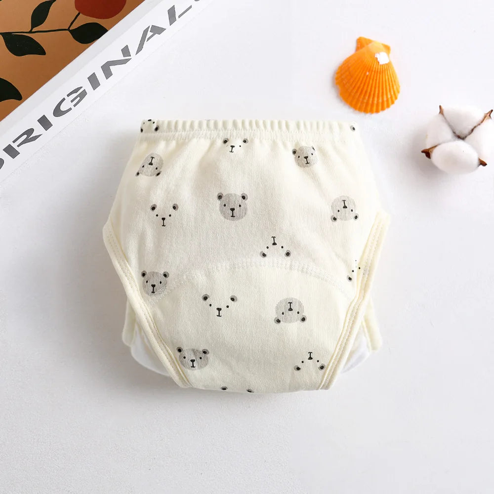 Cream baby cloth diaper training pants with a cute grey bear print pattern. Soft cotton infant baby care apparel.